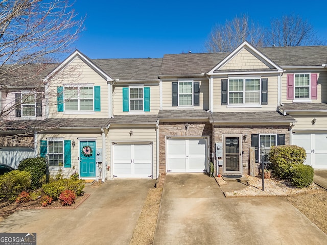 view of property featuring stone siding, driveway, and an attached garage