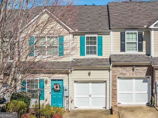 townhome / multi-family property featuring a garage, stone siding, a shingled roof, and driveway