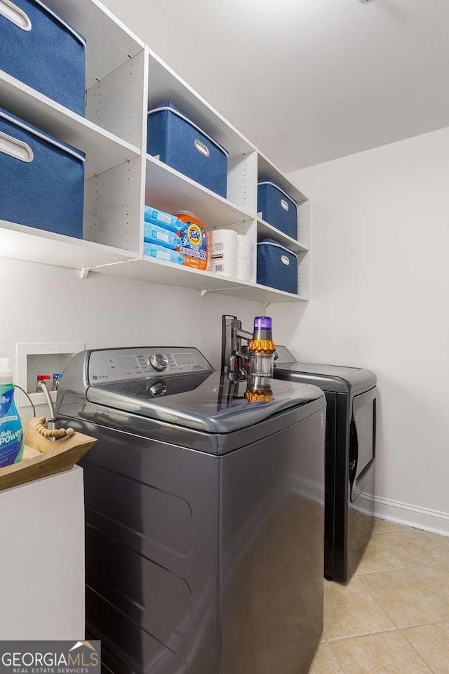 washroom featuring light tile patterned floors, laundry area, baseboards, and washer and dryer