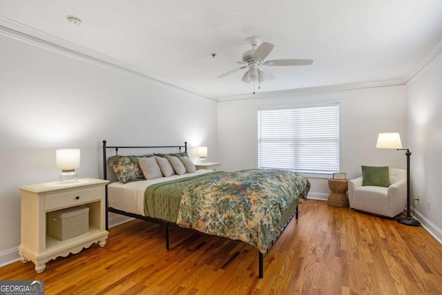 bedroom with a ceiling fan, crown molding, baseboards, and wood finished floors