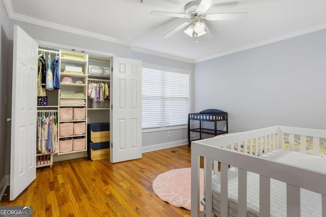 bedroom featuring crown molding, a closet, baseboards, and wood finished floors