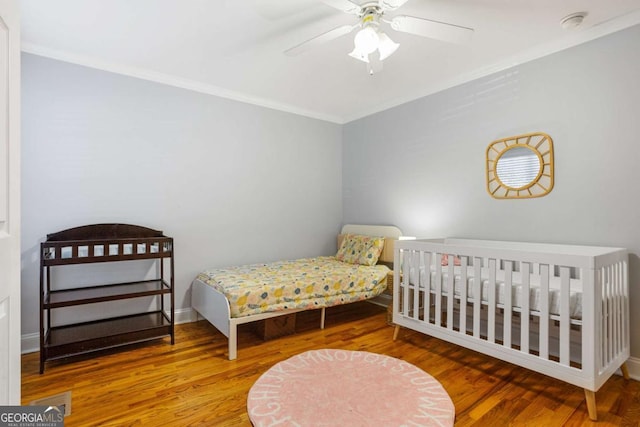 bedroom with ceiling fan, crown molding, baseboards, and wood finished floors