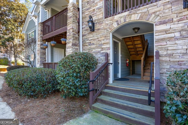 entrance to property with stone siding and a balcony