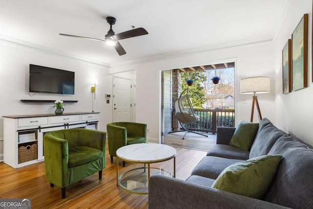 living area with ornamental molding, a ceiling fan, and wood finished floors