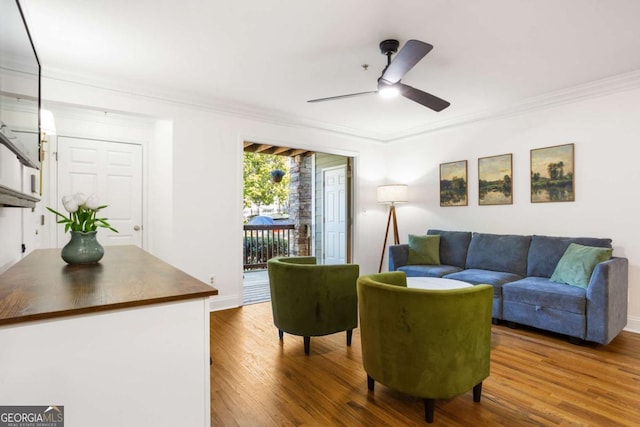 living area featuring ceiling fan, crown molding, baseboards, and wood finished floors