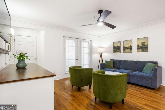 living area featuring french doors, ornamental molding, ceiling fan, wood finished floors, and baseboards