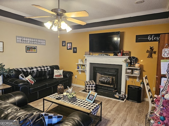 living area with a textured ceiling, a fireplace, wood finished floors, and crown molding