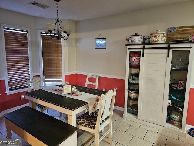 dining space with a chandelier, tile patterned floors, visible vents, and a barn door