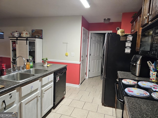 kitchen featuring dark countertops, black appliances, white cabinetry, a sink, and light tile patterned flooring