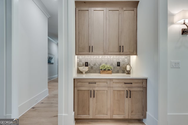 bar with tasteful backsplash, baseboards, and light wood finished floors