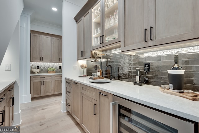 bar featuring recessed lighting, light wood-style flooring, decorative backsplash, a sink, and beverage cooler