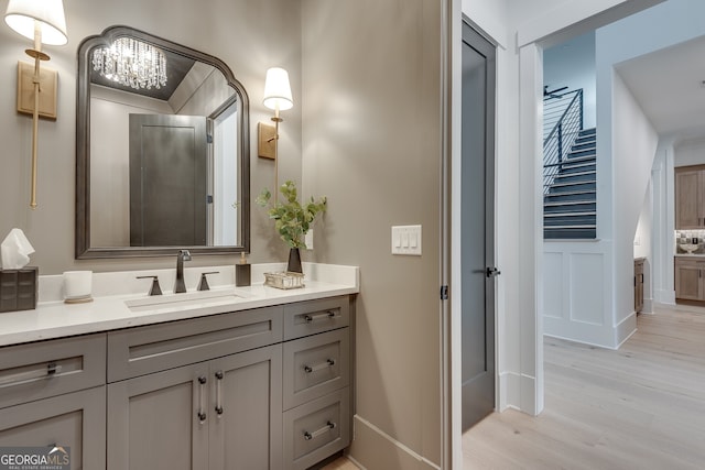 bathroom with baseboards, a notable chandelier, wood finished floors, and vanity