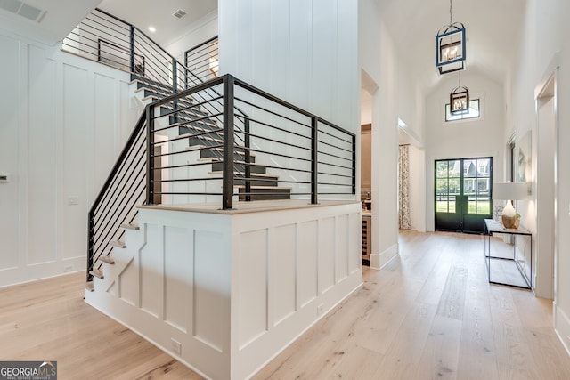 foyer featuring light wood-style flooring, stairs, visible vents, and a decorative wall