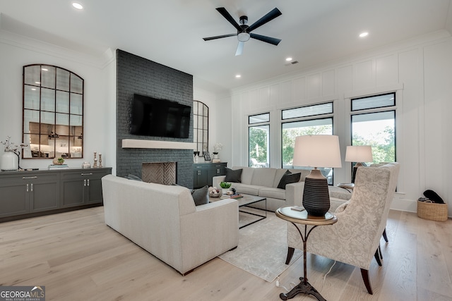 living area featuring recessed lighting, a fireplace, light wood-style flooring, and crown molding