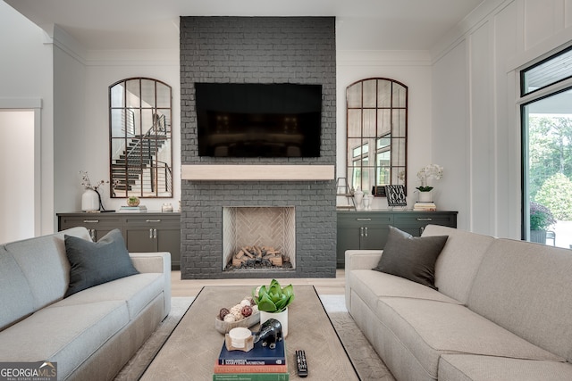 living room featuring a brick fireplace and ornamental molding