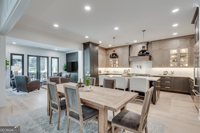 dining space with ornamental molding, recessed lighting, french doors, and light wood-style flooring