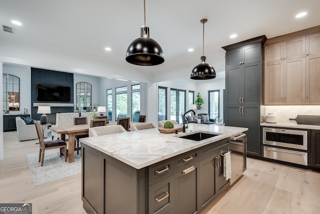 kitchen with open floor plan, a warming drawer, a sink, and light wood-style floors