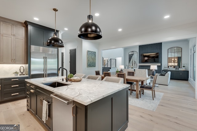 kitchen with light wood-style flooring, open floor plan, a kitchen island with sink, stainless steel appliances, and a sink