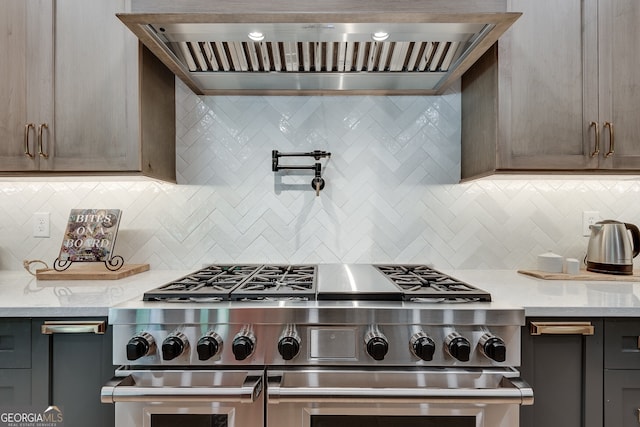 kitchen with double oven range, backsplash, and wall chimney exhaust hood