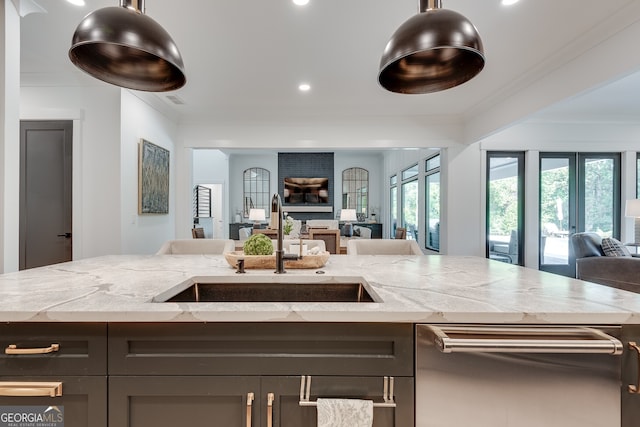 kitchen featuring dishwasher, ornamental molding, open floor plan, light stone countertops, and a sink