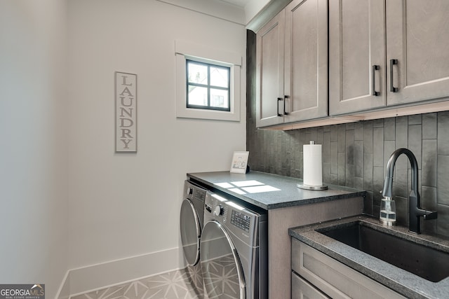 laundry area with a sink, washing machine and clothes dryer, cabinet space, and baseboards