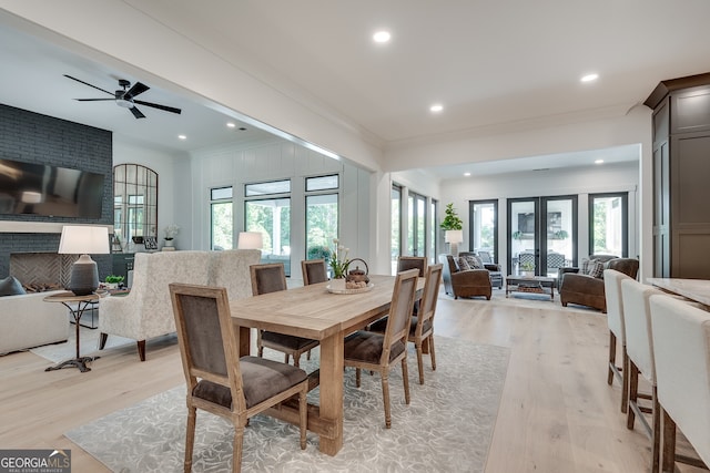 dining space featuring french doors, crown molding, a fireplace, light wood finished floors, and recessed lighting