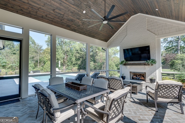 sunroom / solarium featuring lofted ceiling, ceiling fan, an outdoor brick fireplace, and wooden ceiling