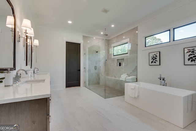 full bathroom featuring ornamental molding, a stall shower, a freestanding tub, and a sink