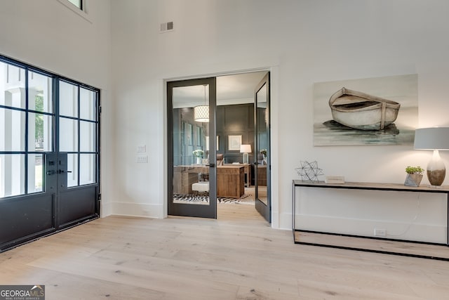 entrance foyer featuring baseboards, visible vents, wood finished floors, and french doors