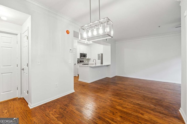 unfurnished living room featuring baseboards, dark wood-style flooring, a sink, and crown molding