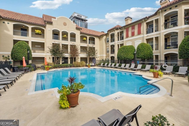 community pool with a patio and fence