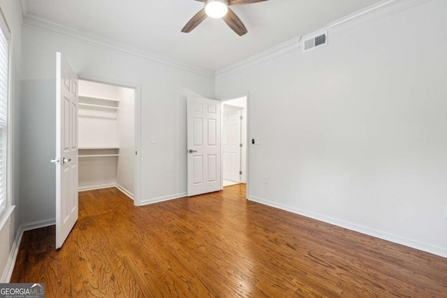 unfurnished bedroom with visible vents, crown molding, baseboards, and wood finished floors