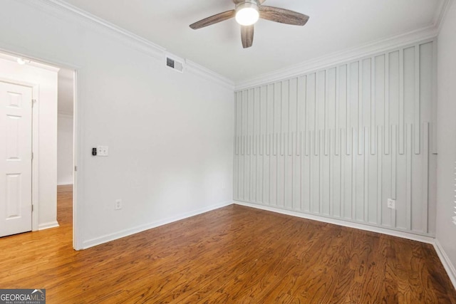 empty room featuring ornamental molding, visible vents, and wood finished floors