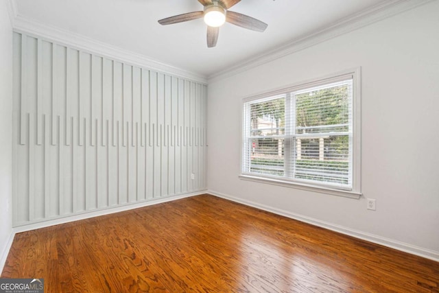 empty room with baseboards, ceiling fan, wood finished floors, and crown molding