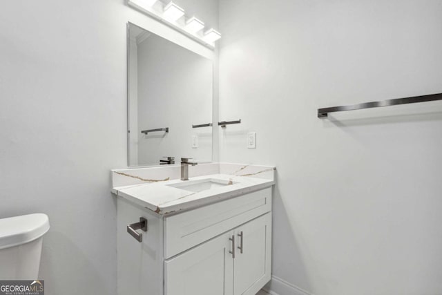 bathroom with toilet, baseboards, and vanity