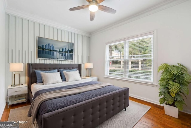 bedroom with baseboards, wood finished floors, a ceiling fan, and crown molding