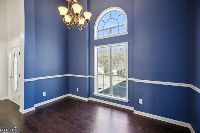 interior space featuring a chandelier, a high ceiling, baseboards, and wood finished floors