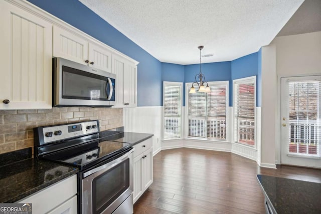 kitchen featuring appliances with stainless steel finishes, dark wood-style flooring, visible vents, and decorative backsplash