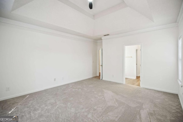 empty room with ornamental molding, a tray ceiling, carpet flooring, and baseboards