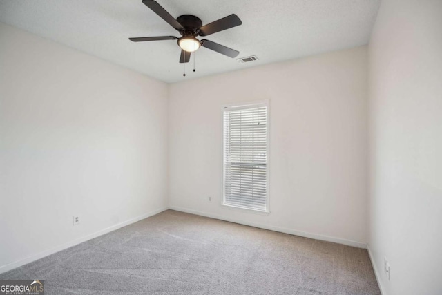 empty room featuring carpet, visible vents, and baseboards