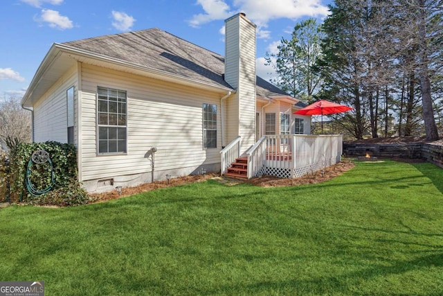 back of house with a deck, roof with shingles, crawl space, a lawn, and a chimney