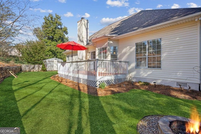 view of yard with a shed, a fire pit, a deck, and an outbuilding