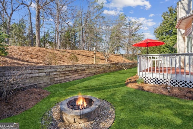 view of yard featuring an outdoor fire pit and a deck