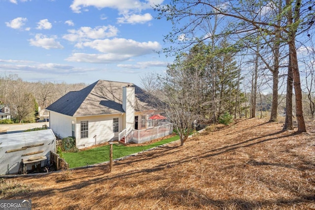 view of property exterior featuring roof with shingles, a lawn, and a chimney