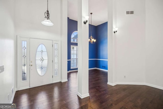 entrance foyer featuring a towering ceiling, baseboards, visible vents, and wood finished floors