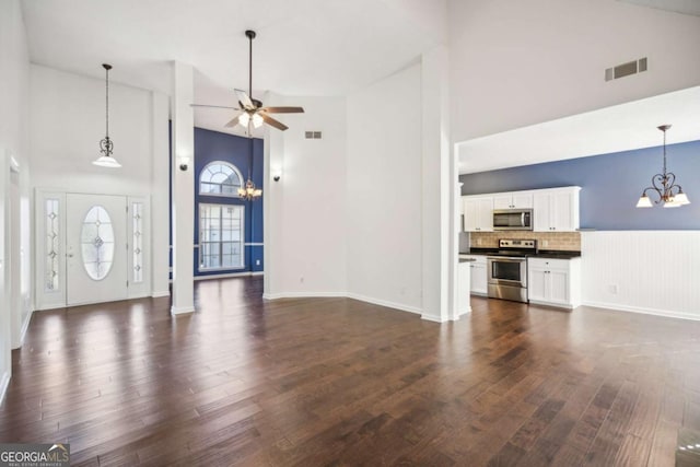 foyer with dark wood-style flooring, visible vents, high vaulted ceiling, baseboards, and ceiling fan with notable chandelier