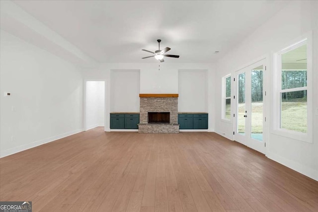 unfurnished living room with ceiling fan, a fireplace, wood finished floors, and baseboards