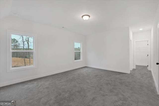 unfurnished room featuring dark carpet, a wealth of natural light, and baseboards