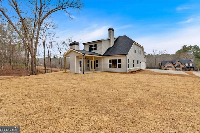 back of property featuring ceiling fan, a shingled roof, a chimney, and a lawn