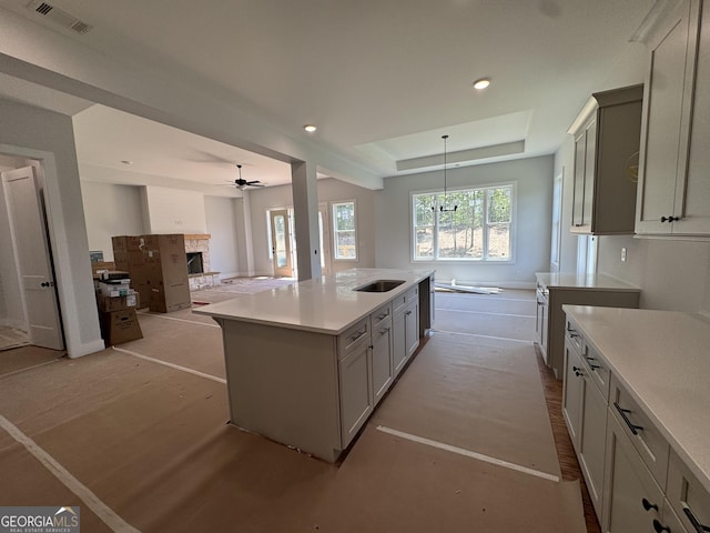 kitchen with ceiling fan, visible vents, open floor plan, light countertops, and a fireplace